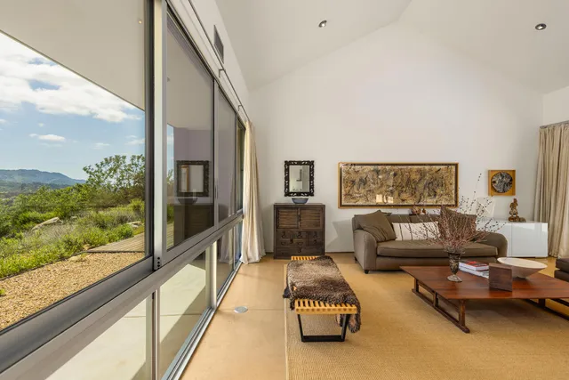 a large white bed sitting in a bedroom next to a window