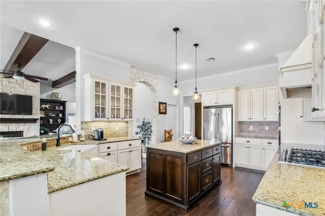 a kitchen with granite countertop a stove a sink and a refrigerator
