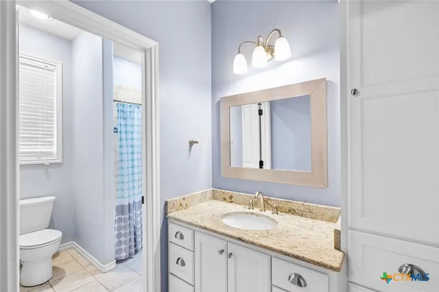 a bathroom with a granite countertop sink a toilet and a mirror