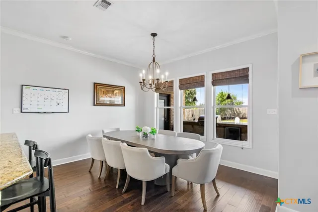 a kitchen with stainless steel appliances a dining table chairs and wooden floor