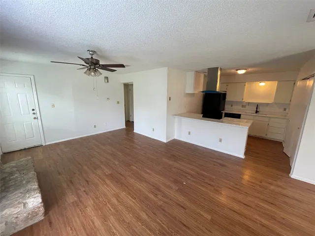 a view of a electric appliances in kitchen and empty room with wooden floor