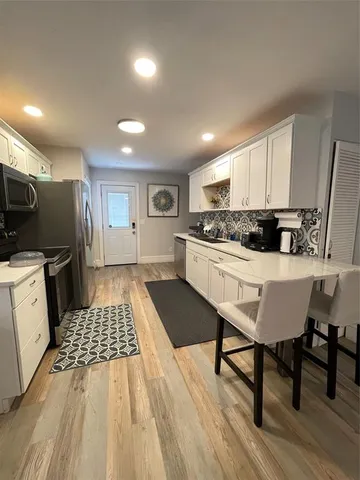 a kitchen with stainless steel appliances a stove a sink a microwave a refrigerator and cabinets