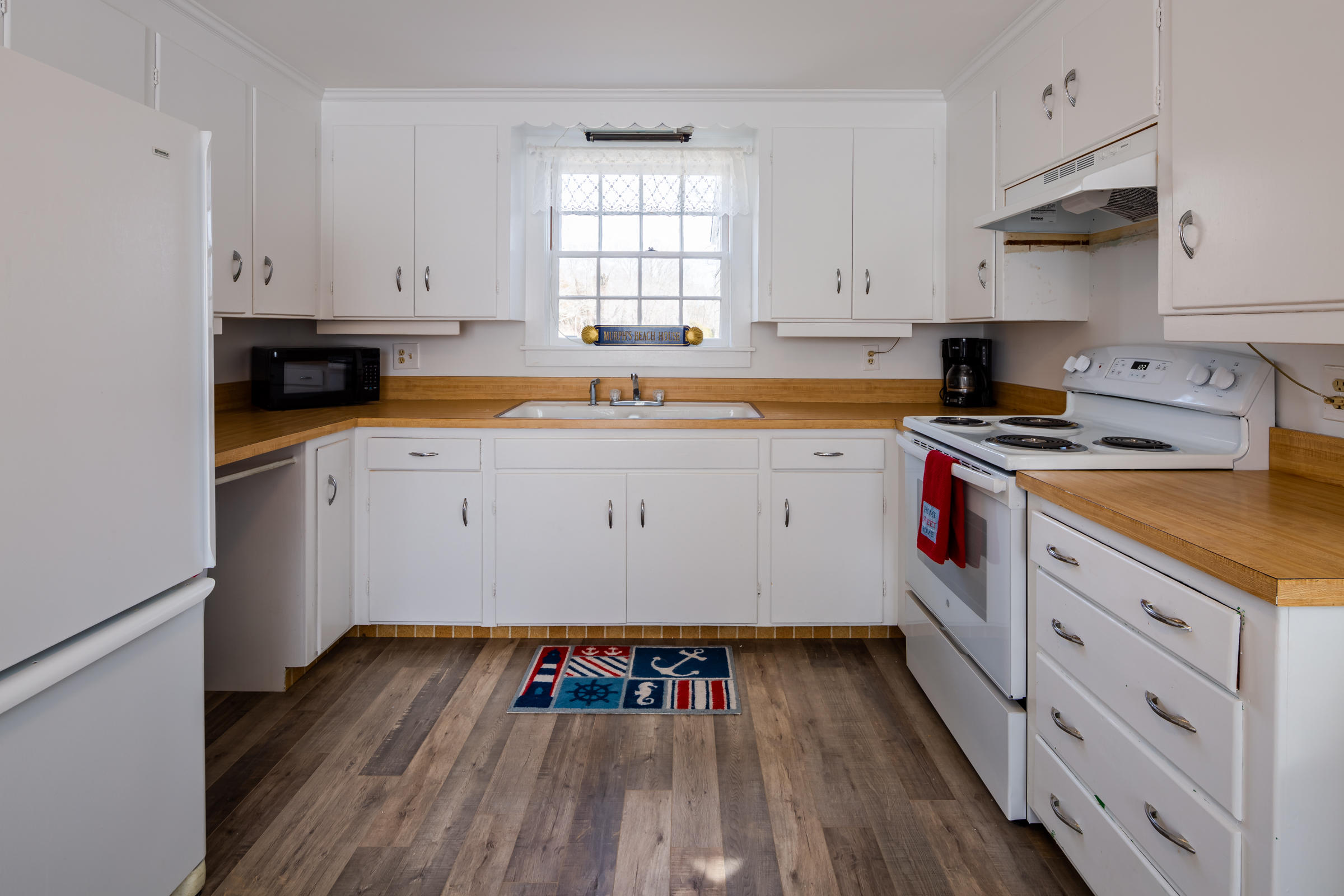 700 Main Street Cotuit, MA 02635 - Photo 6 of 20 a kitchen with wooden floors and white appliances