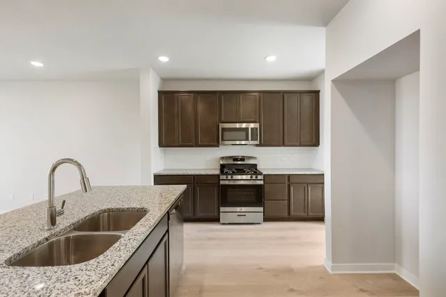 a kitchen with kitchen island granite countertop a sink stove top oven and refrigerator