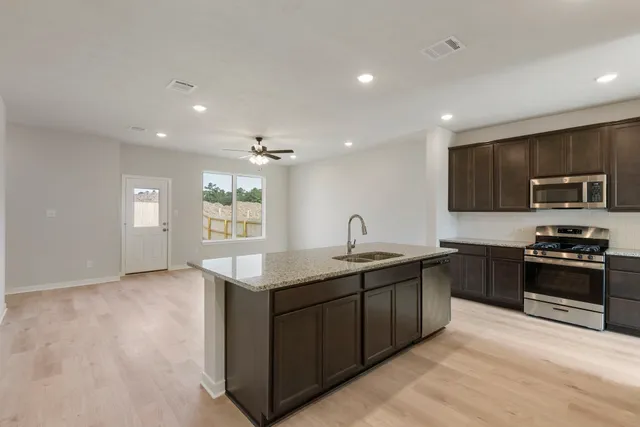 a kitchen with stainless steel appliances granite countertop a sink and stove top oven with wooden floor