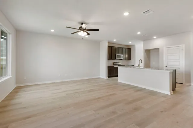 a view of a kitchen with a sink a ceiling fan and stainless steel appliances