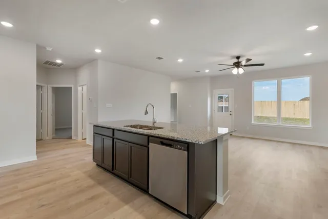a kitchen with stainless steel appliances granite countertop a sink and a large window