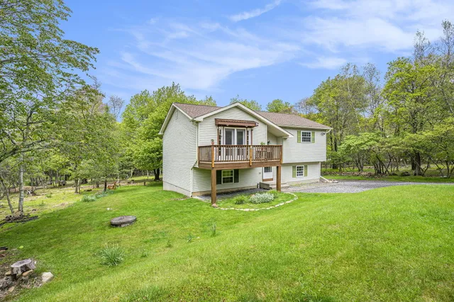 a view of a house with a big yard and large trees