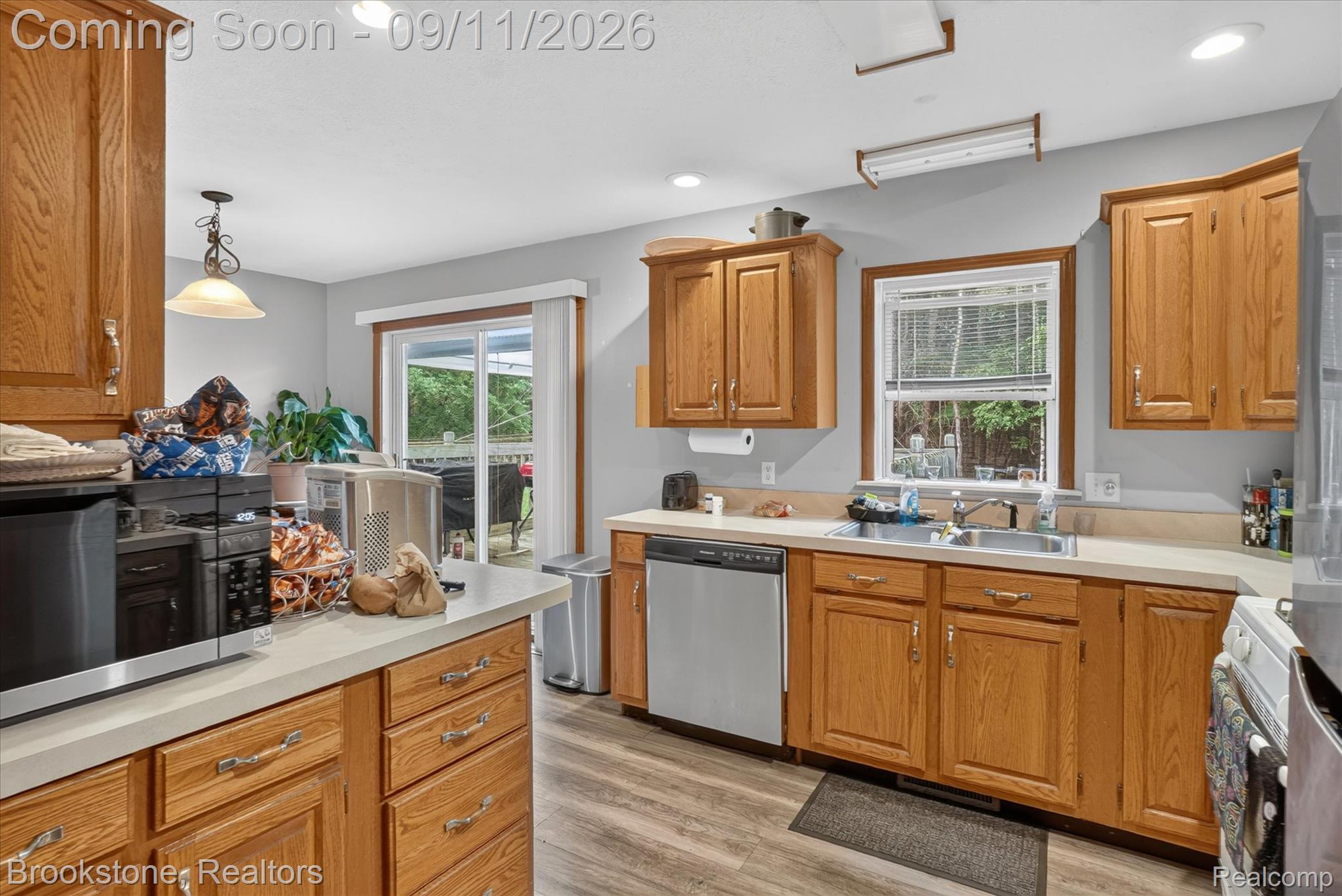 1812 South Steel Road Merrill, MI 48637 - Photo 11 of 39 Kitchen featuring wood-finish cabinetry, light countertops, wood-finish flooring, stainless steel dishwasher, and a sliding glass door