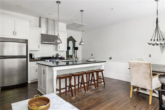 a kitchen with stainless steel appliances granite countertop a stove a sink dishwasher a refrigerator and a dining table with wooden floor