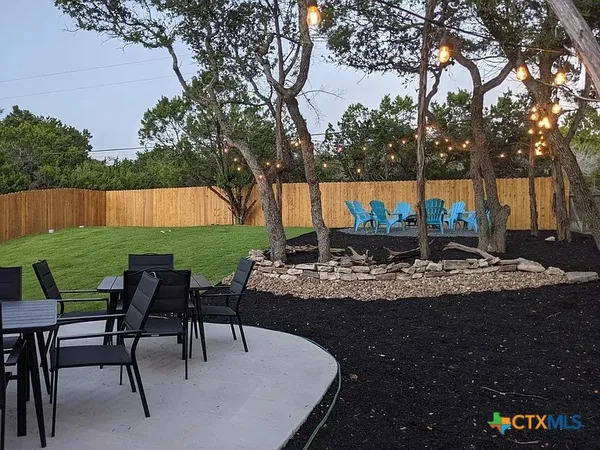 a view of backyard with table and chairs and a large tree