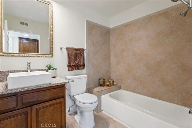 a bathroom with a granite countertop sink a toilet and bathtub