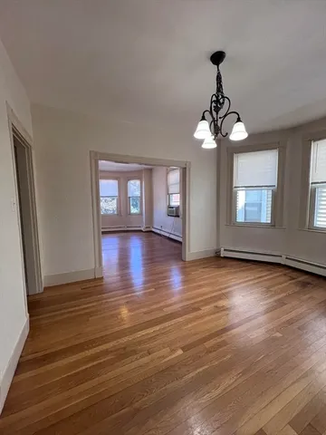 a view of a room with wooden floor chandelier and windows
