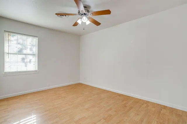 an empty room with a window and a fan