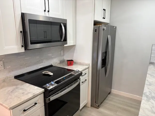 a kitchen with stainless steel appliances granite countertop a refrigerator stove and microwave