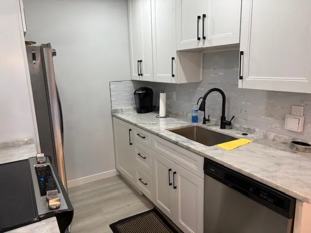 a kitchen with granite countertop a sink stove and refrigerator