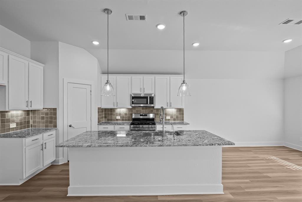 562 Bluebell Maiden Court Magnolia, TX 77354 - Photo 2 of 13 a kitchen with kitchen island granite countertop a sink a counter space appliances and cabinets