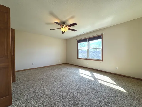 a bedroom with a bed a chair and a large window