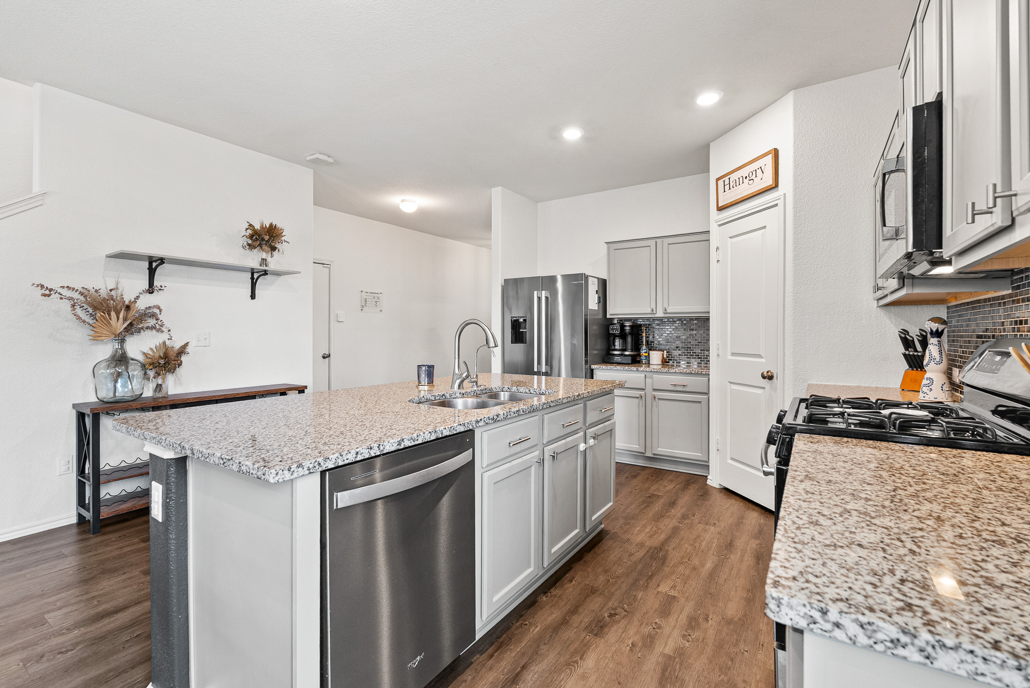 136 Copper Lane Kyle, TX 78640 - Photo 29 of 33 Kitchen with tasteful backsplash, stainless steel appliances, dark wood finished floors, an island with sink, and light stone counters
