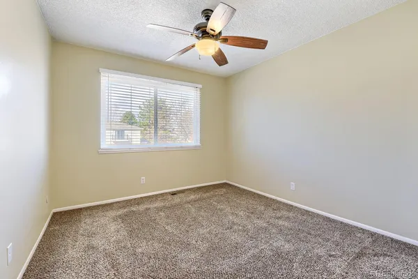 an empty room with windows and fan