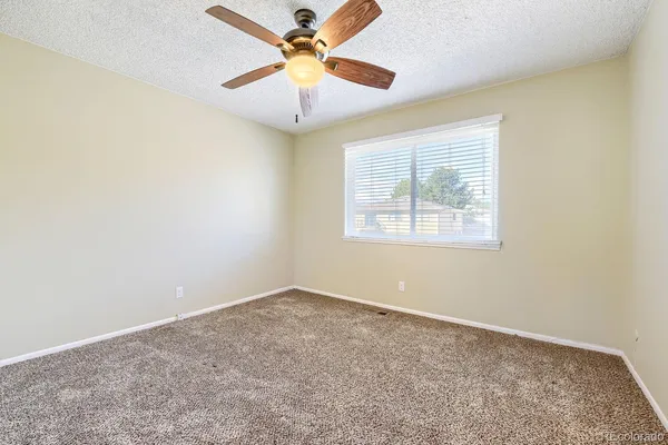 an empty room with a window and a fan