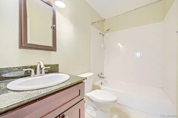 a bathroom with a granite countertop sink toilet a mirror and shower