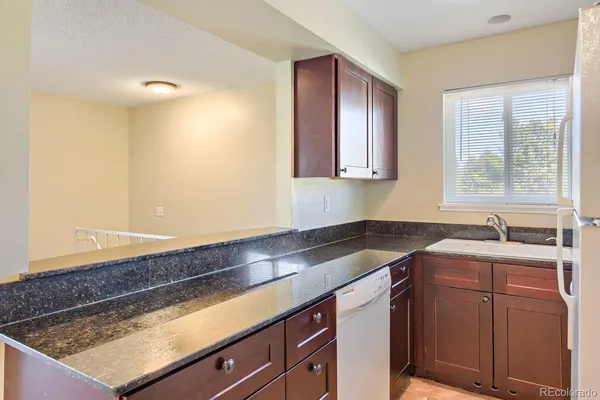a kitchen with a sink dishwasher and cabinets with wooden floor