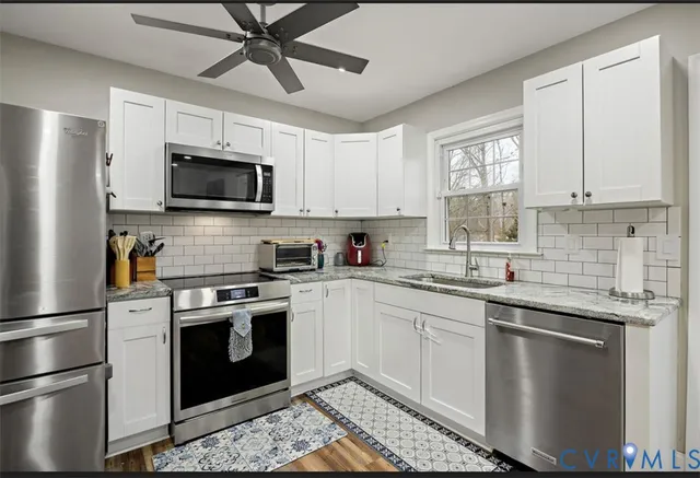 a kitchen with cabinets stainless steel appliances a sink and a window