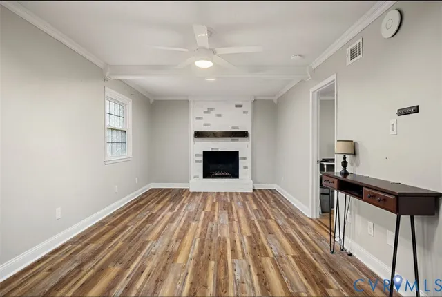 a view of empty room with a fireplace and wooden floor
