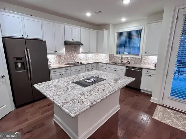 a kitchen with kitchen island granite countertop wooden cabinets and a refrigerator