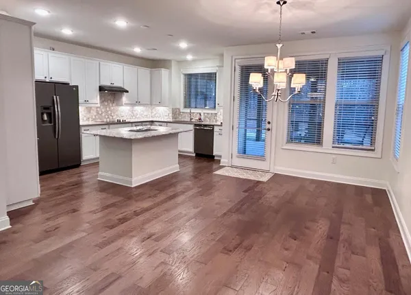 a view of a kitchen with stainless steel appliances wooden floor and a refrigerator