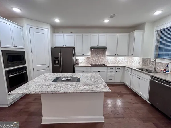 a kitchen with kitchen island granite countertop a sink stove and refrigerator