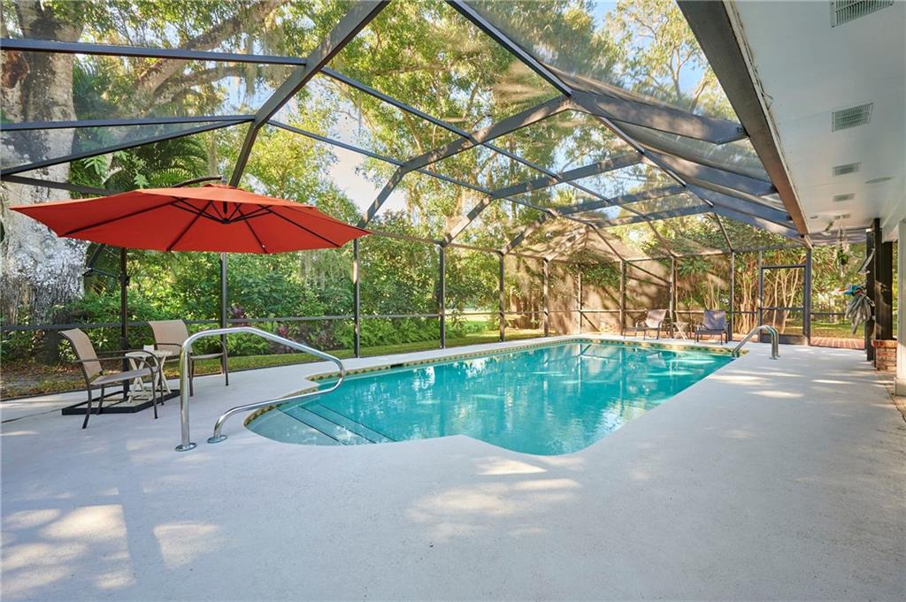 1565 48th Avenue Vero Beach, FL 32966 - Photo 20 of 34 a view of pool with a table and chairs under an umbrella