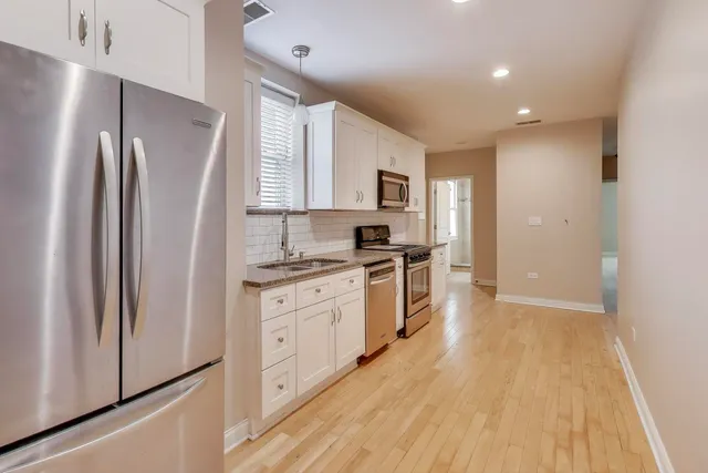 a kitchen with white cabinets and stainless steel appliances