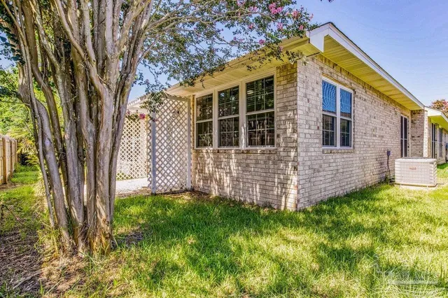 a view of a house with a small yard and a large tree