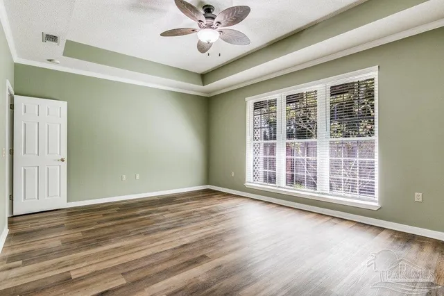 a view of an empty room with window and wooden floor