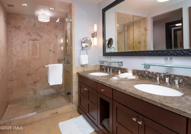 a bathroom with a granite countertop sink a mirror and a shower