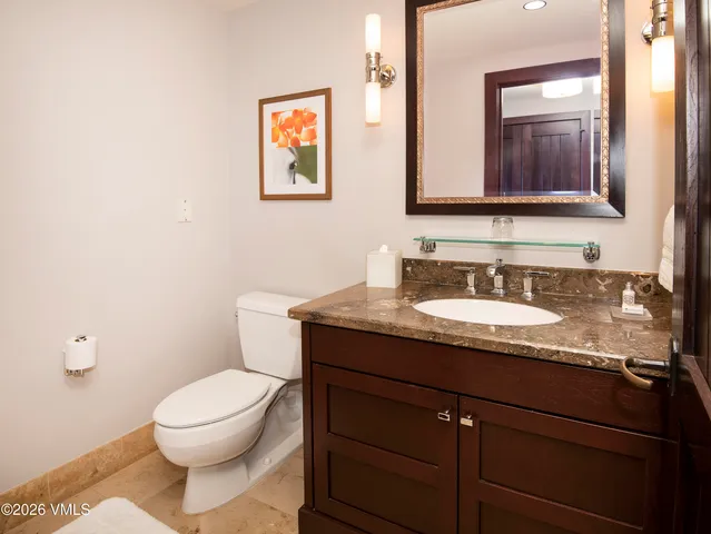 a bathroom with a granite countertop toilet sink and mirror