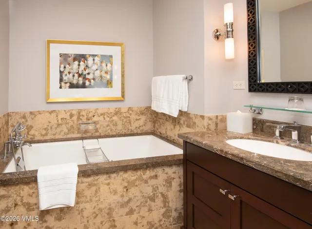 a bathroom with a granite countertop bathtub sink and mirror