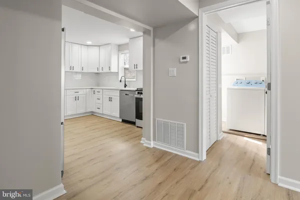 a kitchen with white cabinets and wooden floor