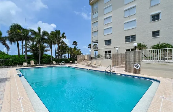 a view of swimming pool with outdoor seating and house in the background