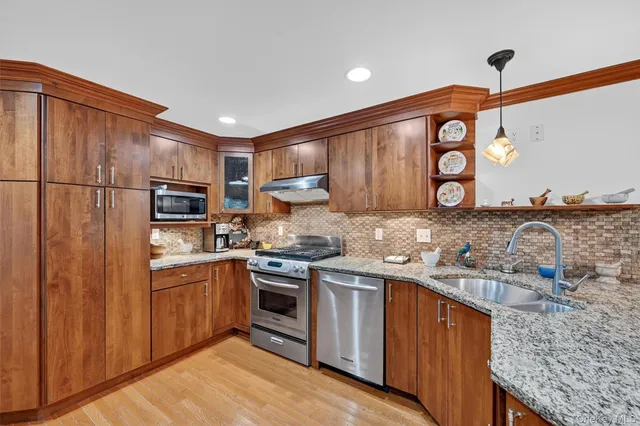 a kitchen with stainless steel appliances granite countertop a stove top oven a sink and a refrigerator