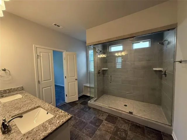 a bathroom with a granite countertop sink a toilet and shower