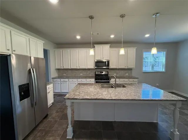 a kitchen with kitchen island a refrigerator a sink cabinets and wooden floor