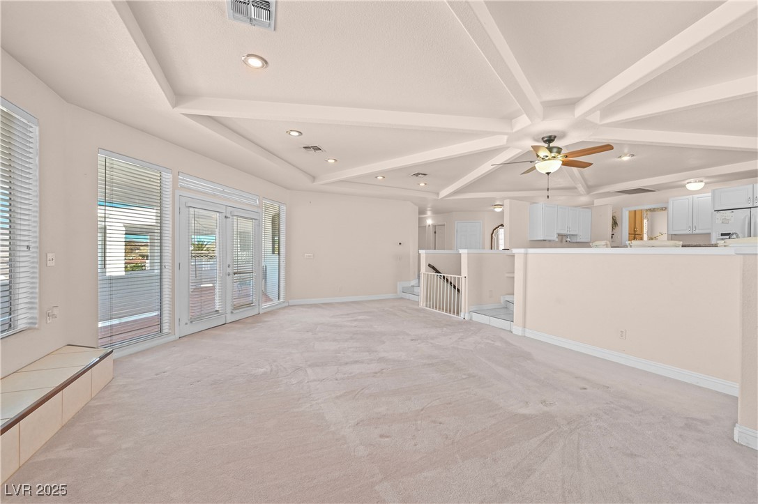 736 Kiel Street Henderson, NV 89015 - Photo 11 of 38 Unfurnished living room featuring baseboards, visible vents, beamed ceiling, and light colored carpet