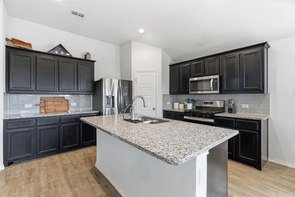 a kitchen with kitchen island granite countertop stainless steel appliances and wooden cabinets