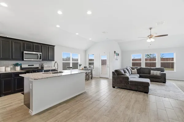 a living room with stainless steel appliances kitchen island granite countertop a couch and a view of living room