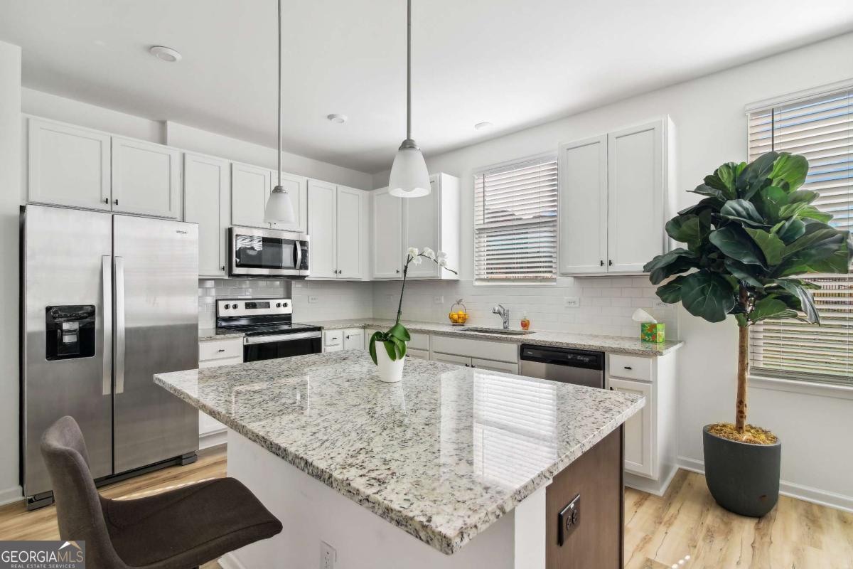 1453 Proust Lane, Unit 1453 Stockbridge, GA 30281 - Photo 6 of 26 a kitchen with stainless steel appliances granite countertop a sink a stove a refrigerator a center island cabinets and wooden floor