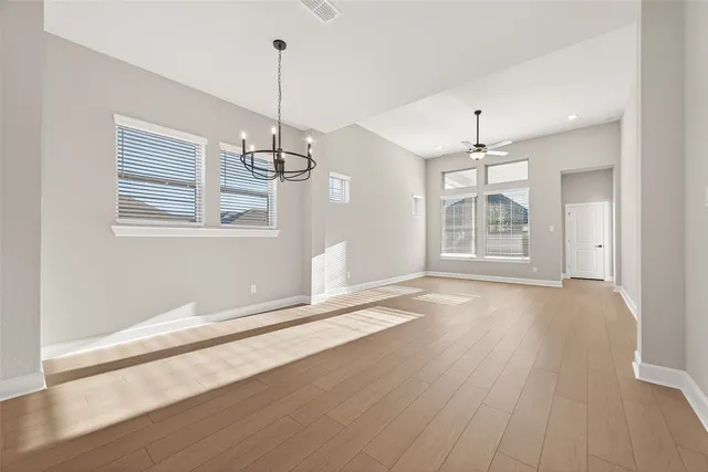 a view of empty room with a window and chandelier
