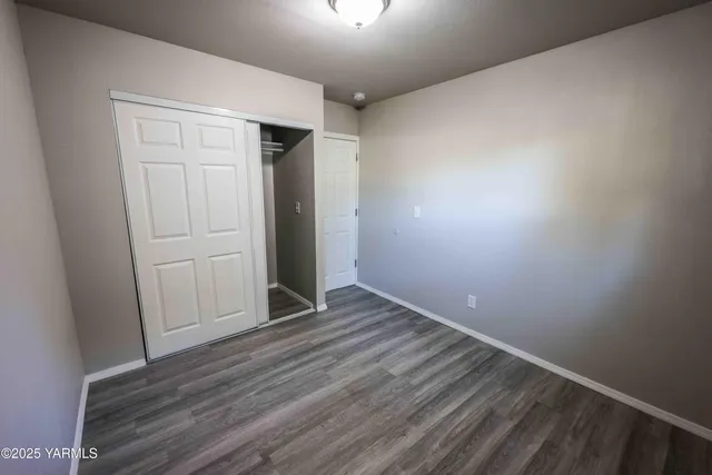 a view of an empty room with closet and wooden floor
